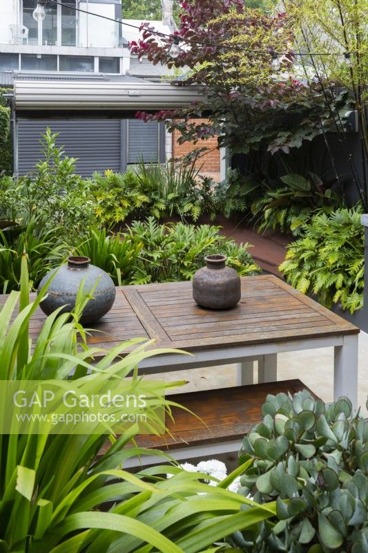 An outdoor table and bench seat with decorative hand made metal pots.