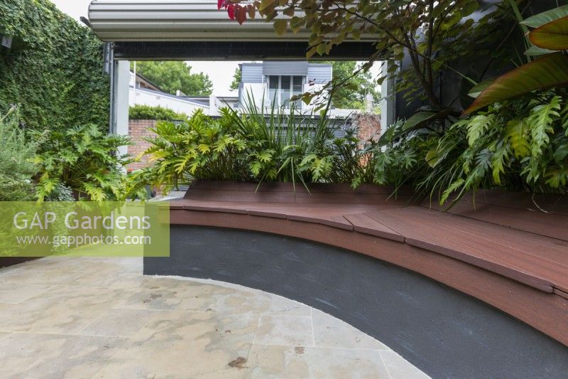 Inner city courtyard garden with inbuilt curved composite timber bench seating.