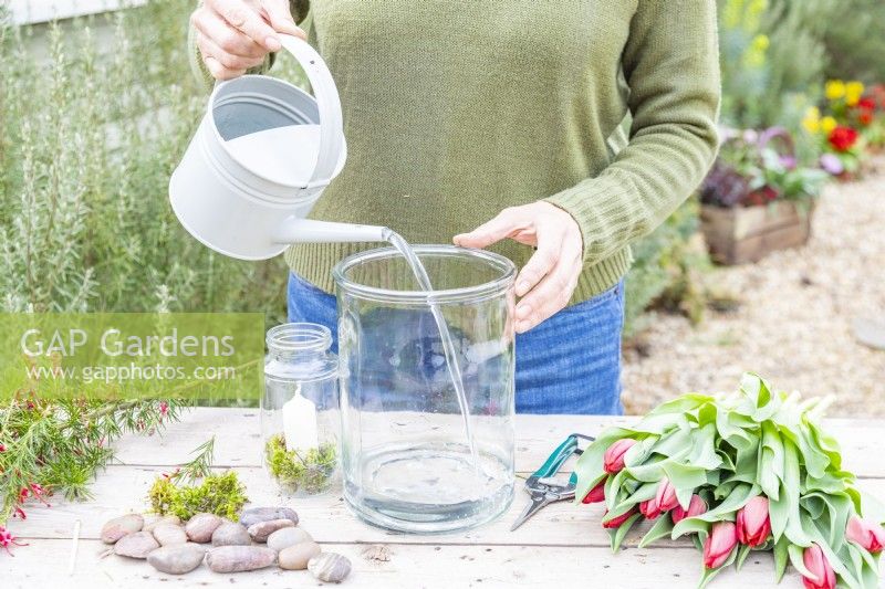Woman pouring water in the large glass container