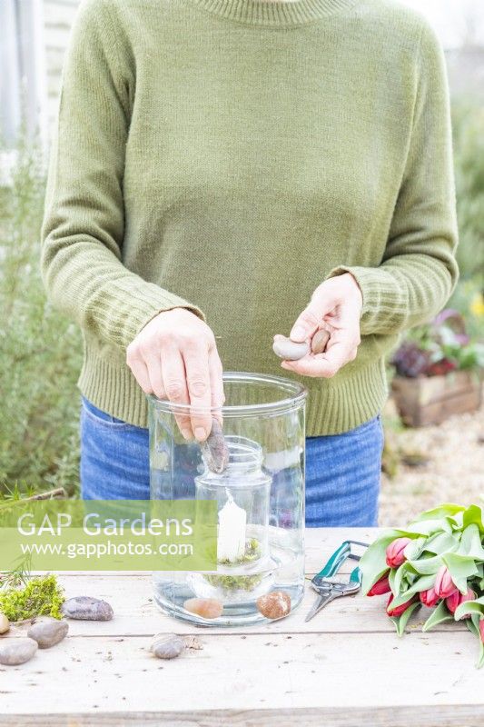 Woman placing pebbles in the large glass container