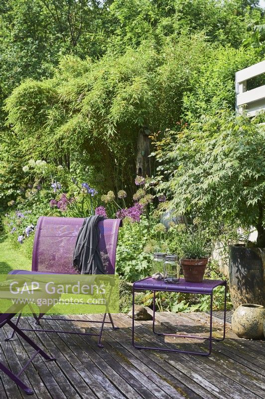Purple furniture on wooden decking, view to garden behind