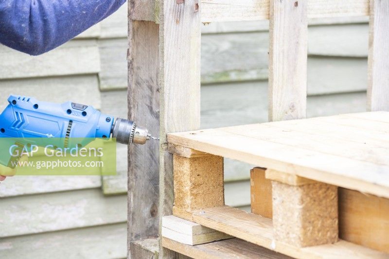 Woman drilling pilot hole into the pallets