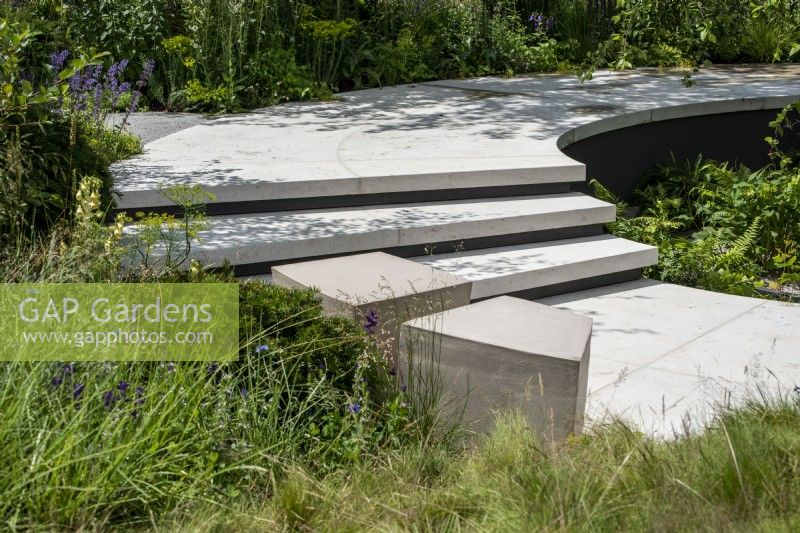 Curved steps leading to a path around a sunken garden.  The Cancer Research Legacy Garden, RHS Hampton Court Palace Garden Festival 2021