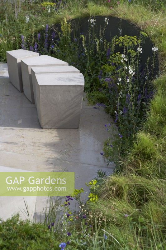 The Cancer Research UK Legacy Garden. Designer: Tom Simpson. Modern pale stone seating area. RHS Hampton Court Palace Festival 2021