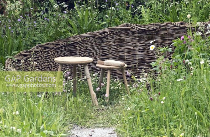 Woven willow enclave in wild garden with wooden stool seats
