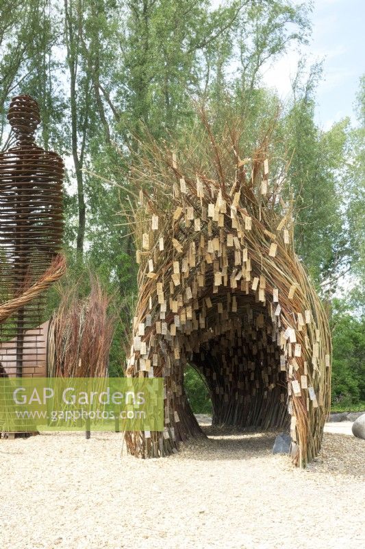 Arch made of willow branches with wooden wish plates made by nature artist Will Beckers.