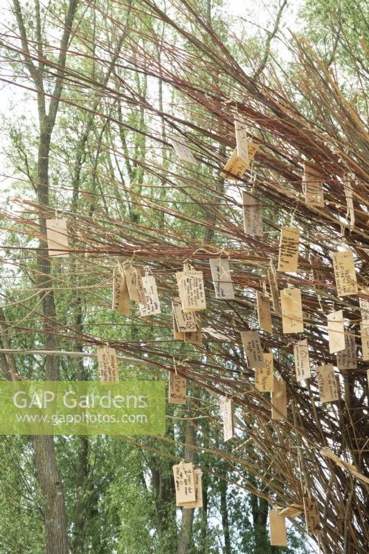 Arch of willow branches filled with wooden wish plates made by nature artist Will Beckers.