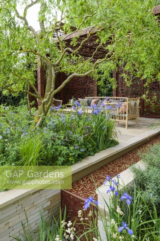 Morris and Co. Garden with  Yorkshire stone water rill inlaid with  metal Willow Boughs pattern, also used on the handcrafted metal pavilion and cushions with Salix matsudana tortuosa tree, dragon's claw willow and  Iris siberica sp