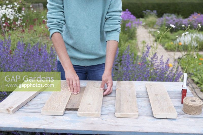 Woman using a small piece of wood as a spacer to evenly position the cut planks of wood