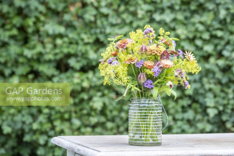 Bouquet containing Verbena bonariensis, Nigella seed pods, Calendula 'Sherbet Fizz', Zinnia 'Queen Red Lime', Nicotiana 'Bronze Queen' and Alchemilla mollis
