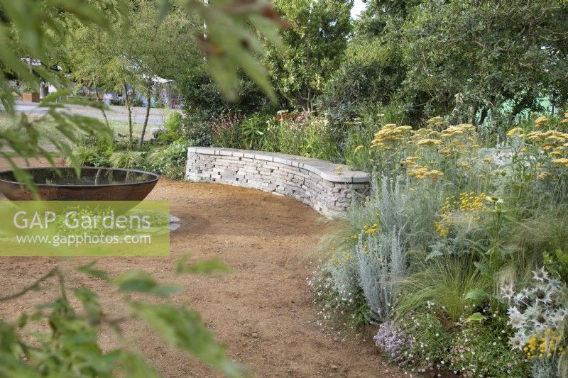 Stone seating area bordered by perennial planting in the RHS Planet-Friendly Garden at RHS Hampton Court Palace Garden Festival 2022