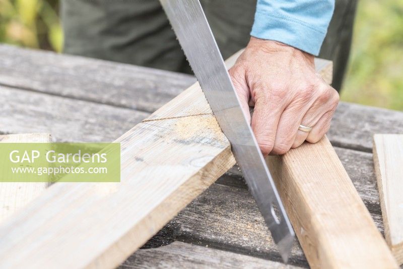 Woman sawing the wooden planks to the correct shape