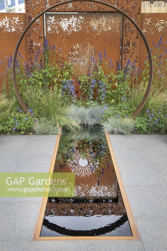Corten steel moongate and reflections in the pool in the Sunburst garden at RHS Hampton Court Palace Garden Festival 2022