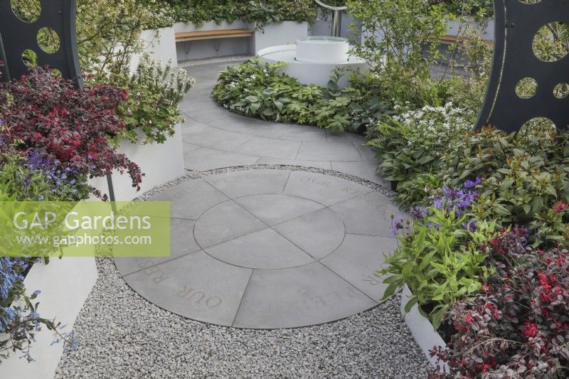 Circular paving bordered by planting in the CRUK Legacy Garden at RHS Malvern Spring Festival 2022