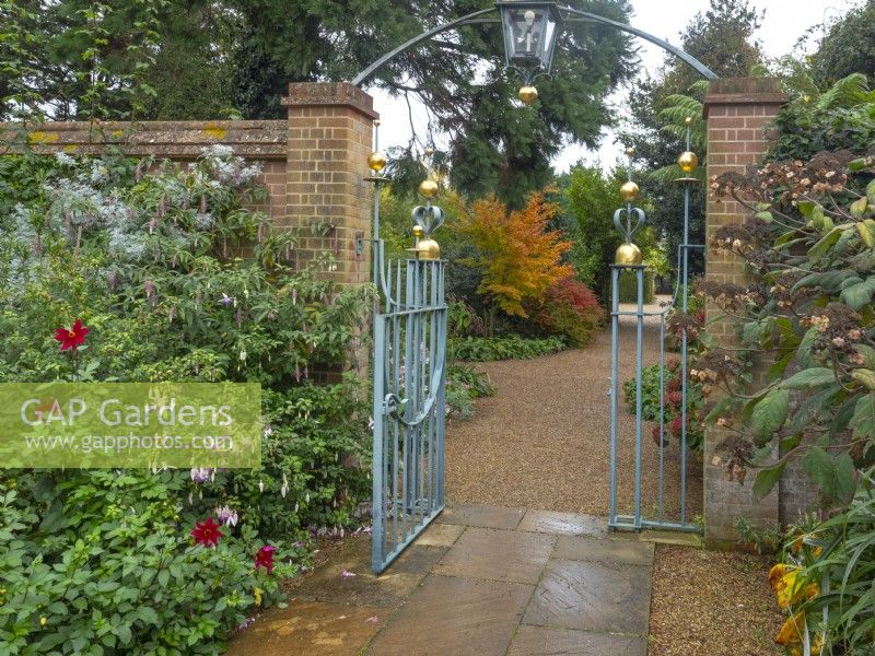 Entrance Court at East Ruston Old Vicarage Gardens, Norfolk, decorative iron work gateway, walls and containers at the beginning of Autumn
