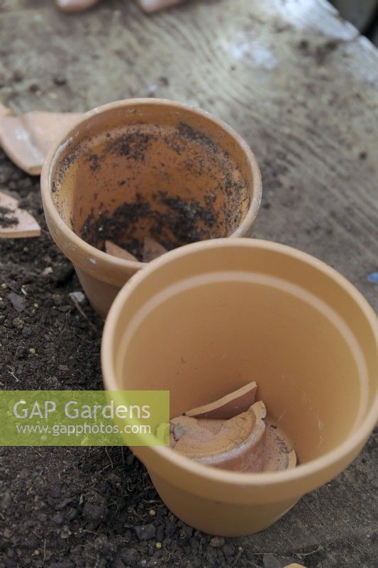 Placing crocks in bottom of terracotta clay pot before adding compost
