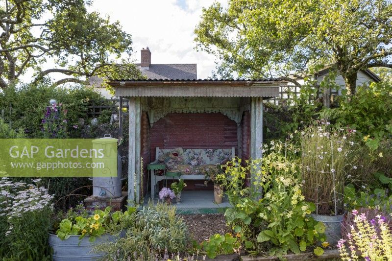 Informal cottage planting around a summerhouse made with recycled materials.