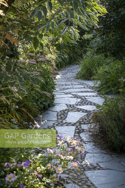 paved and cobbled path through late summer garden