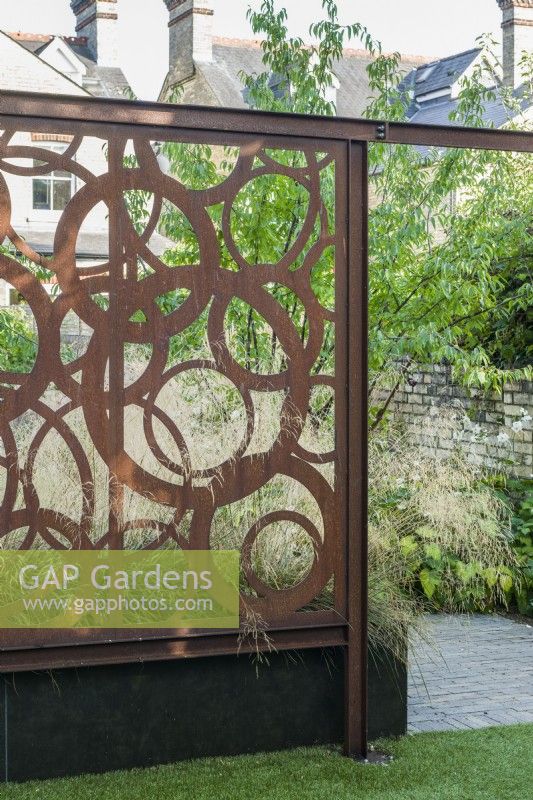 Bespoke corten steel screen in contemporary walled town garden. August
