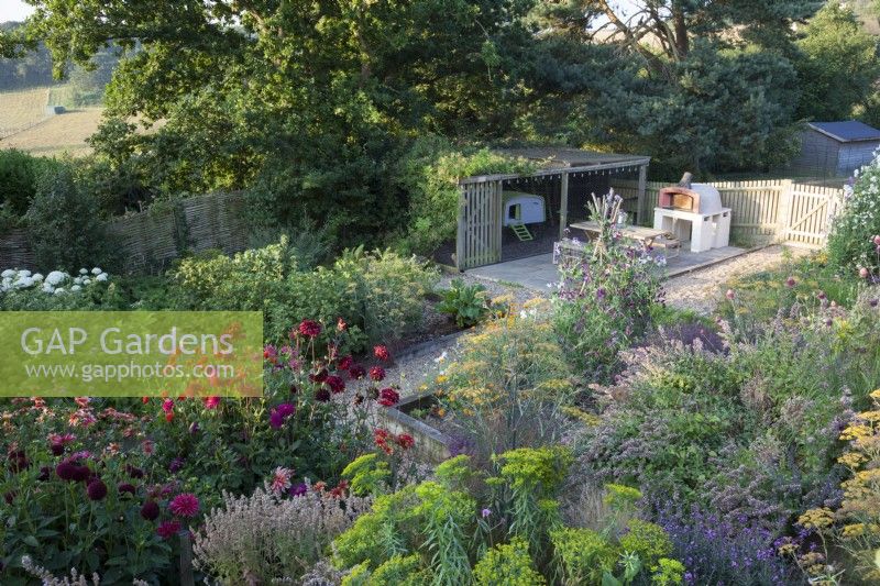 Wide view of the garden with view of fields behind, Chicken coop and pizza oven. Euphorbia ceratocarpa,
Erysimum 'Bowles Mauve',
Foeniculum vulgare ' Purpureum' - Bronze Fennel,
Nepeta 'Dawn to Dusk',
Sweet Pea 'Blue Ripple', 'Hi Scent', and 'Cupani',
Dahlia 'Totally Tangerine', 'Jowey Mirella', 'New Baby', 'Downham Royal', 'Sam
 Hopkins', 'Ambition' and Hydrangea  arborescens 'Annabelle'.