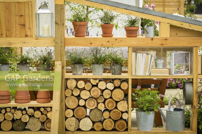 Wooden modular wall storage and display  made from reclaimed timber with logs and Erigeron karvinskianus 'Profusion' - Mexican fleabane in containers in #knollingwithdaisies garden at RHS Hampton Court Palace Garden Festival 2022
