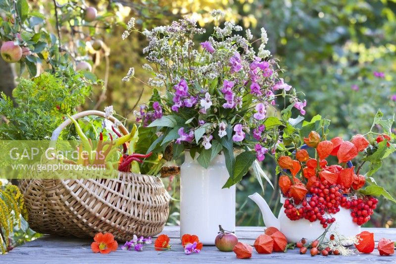 Floral arrangement and harvested vegetables on the table including buckwheat, Himalayan balsam, Chinese lanterns and rowan berries.