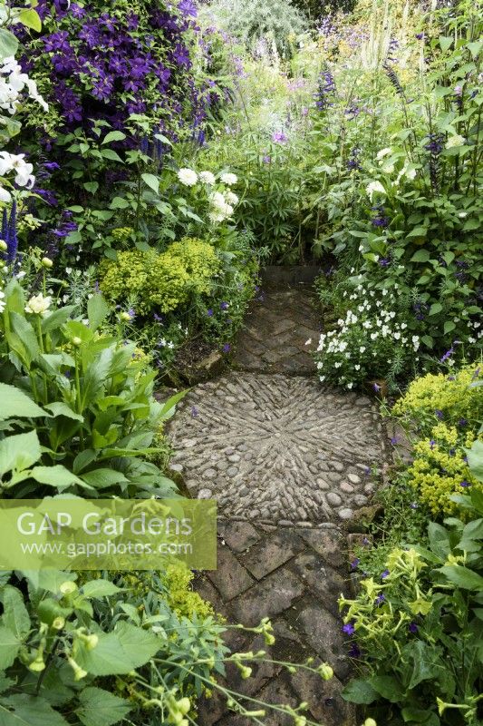 Crossing point of paths marked by a pebble mosaic amongst lush planting in July