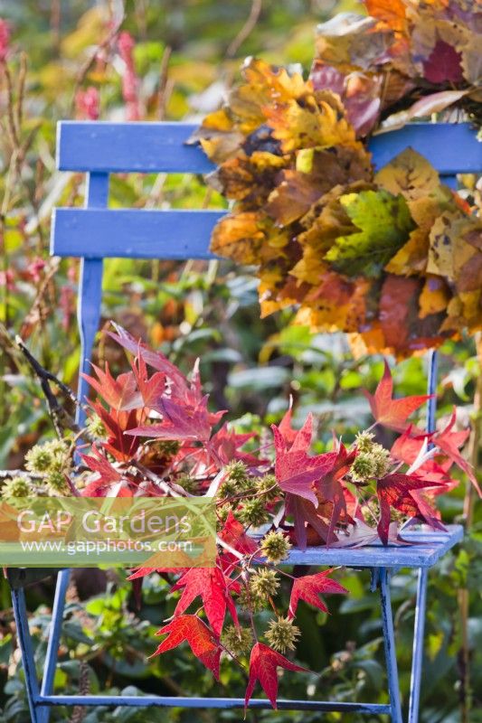 Autumn decoration with Liquidambar foliage and leaf wreath on chair.