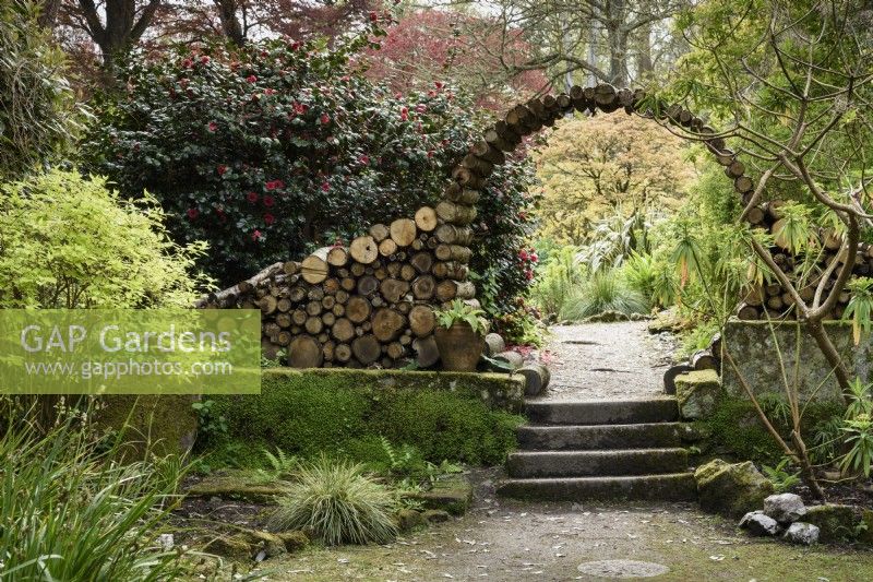 Moon gate made from logs at the entrance to the flower garden at Enys gardens, Cornwall in early May.