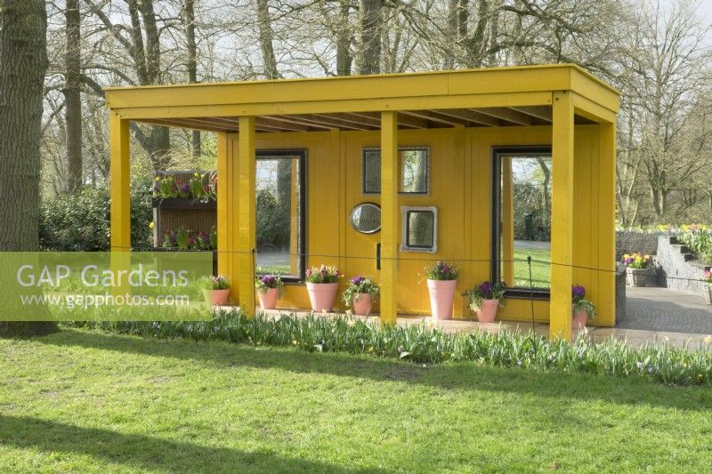 Yellow wooden gazebos decorated with several mirrors.