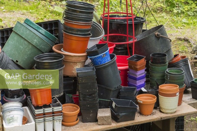 Gardener's potting table with assorted containers in backyard garden in summer