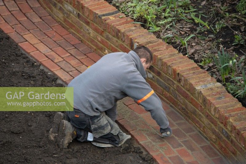 A worker pointing the bricks on a newly built path during the makeover of a London garden.