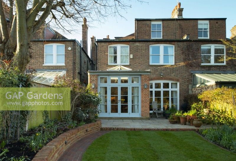 A London garden after a makeover with a new brick wall, path, extended terrace and newly laid turf.