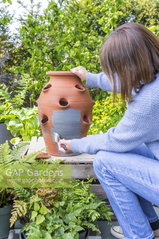 Woman painting the terracotta strawberry planter