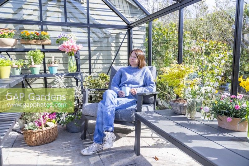 Woman sitting in greenhouse with a cup of tea