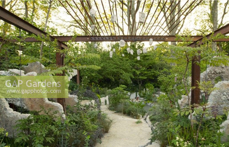 Concrete panels and a metal grid frame a pathway through perennials in the Samaritans' Listening Garden, a Show Garden designed by Darren Hawkes at the RHS Chelsea Flower Show 2023