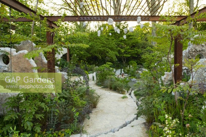 Concrete panels and a metal grid frame a pathway through perennials in the Samaritans' Listening Garden a Show Garden designed by Darren Hawkes at the RHS Chelsea Flower Show 2023