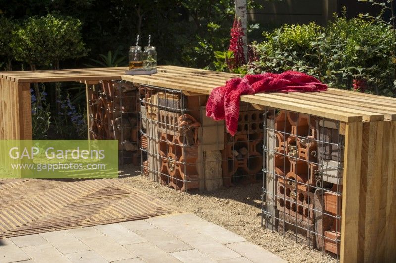 L-shaped slatted wood bench with wildlife bug house underneath - The Beauty in Small Spaces - BBC Gardeners' World Live 2023 - Designers TJ Kennedy and Kerianne Fitzpatrick