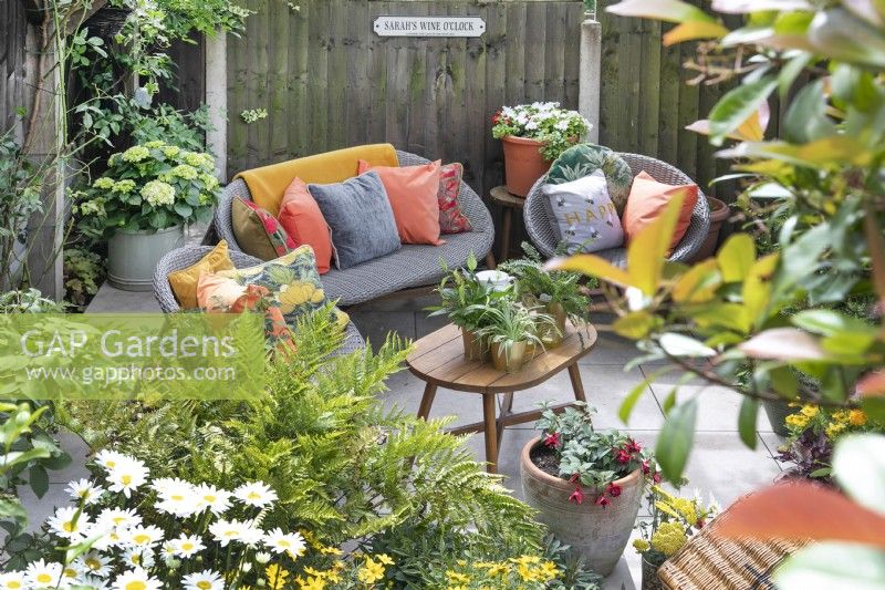 Seating area in small suburban garden in Lichfield, Staffordshire, in red orange and yellow theme, July