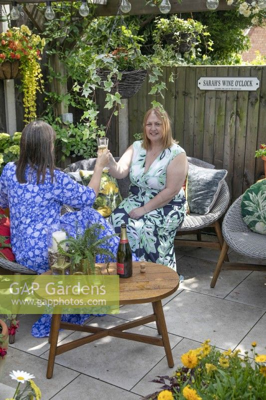 Sarah Hall and friend enjoying wine o'clock  in small suburban garden in Lichfield, Staffordshire, July