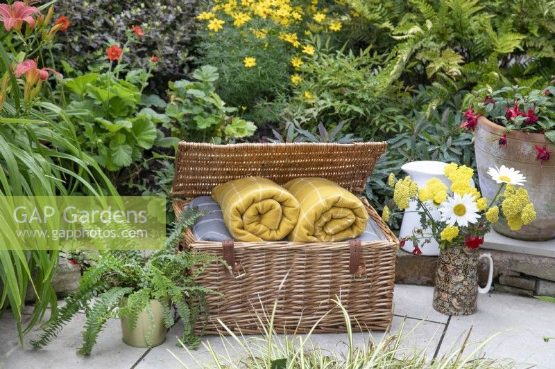 Harrods basket full of blankets in small suburban garden in Lichfield, Staffordshire, in red orange and yellow theme, July