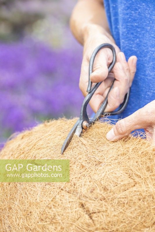 Woman cutting holes in the hanging basket fibre