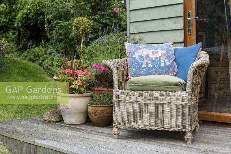 Rattan chair with an Indian cushion in a garden in July