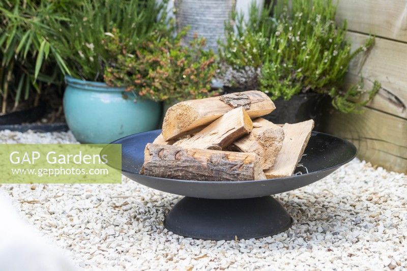 Fire pit in gravel garden with logs
