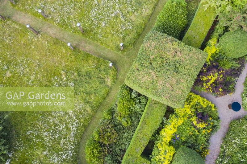 View over block of Hornbeam, clipped hedges of Box, meadow and gravel paths. June, summer. Image taken with drone. 
