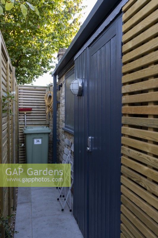 Contemporary wood screens hiding garden utility area with bin and shed