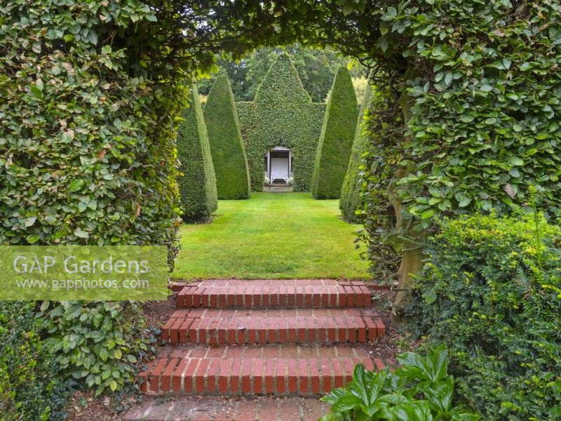 Carpinus hornbeam hedge and arch. Steps to Green Court garden at East Ruston Old Vicarage, Norfolk 