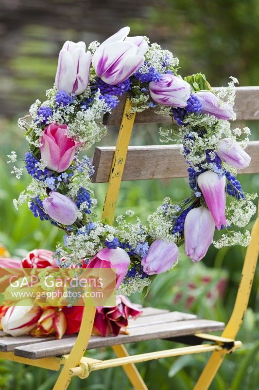 Wreath made of tulips, muscari, cow parsley and myosotis displayed on seat.
