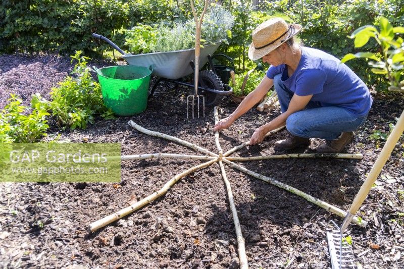 Woman laying out the birch sticks symmetrically from a centre point to create eight sections