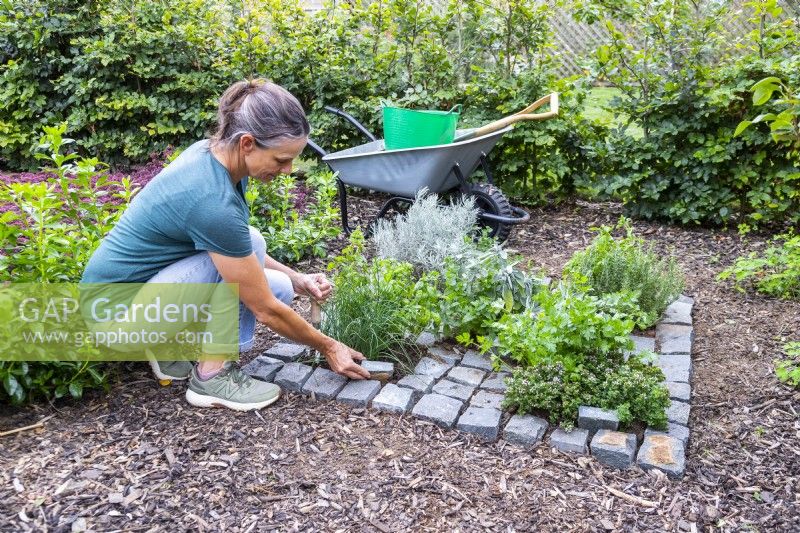 Woman placing granite setts by plants to be used as labels